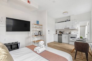 A modern hotel room with a bed, a TV, a kitchenette, and a dining area. - Edmonton Convention Centre Studio | Parking, Wifi (Edmonton)