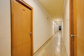 Un pasillo de hotel con puertas de madera, suelo de mármol e iluminación empotrada.