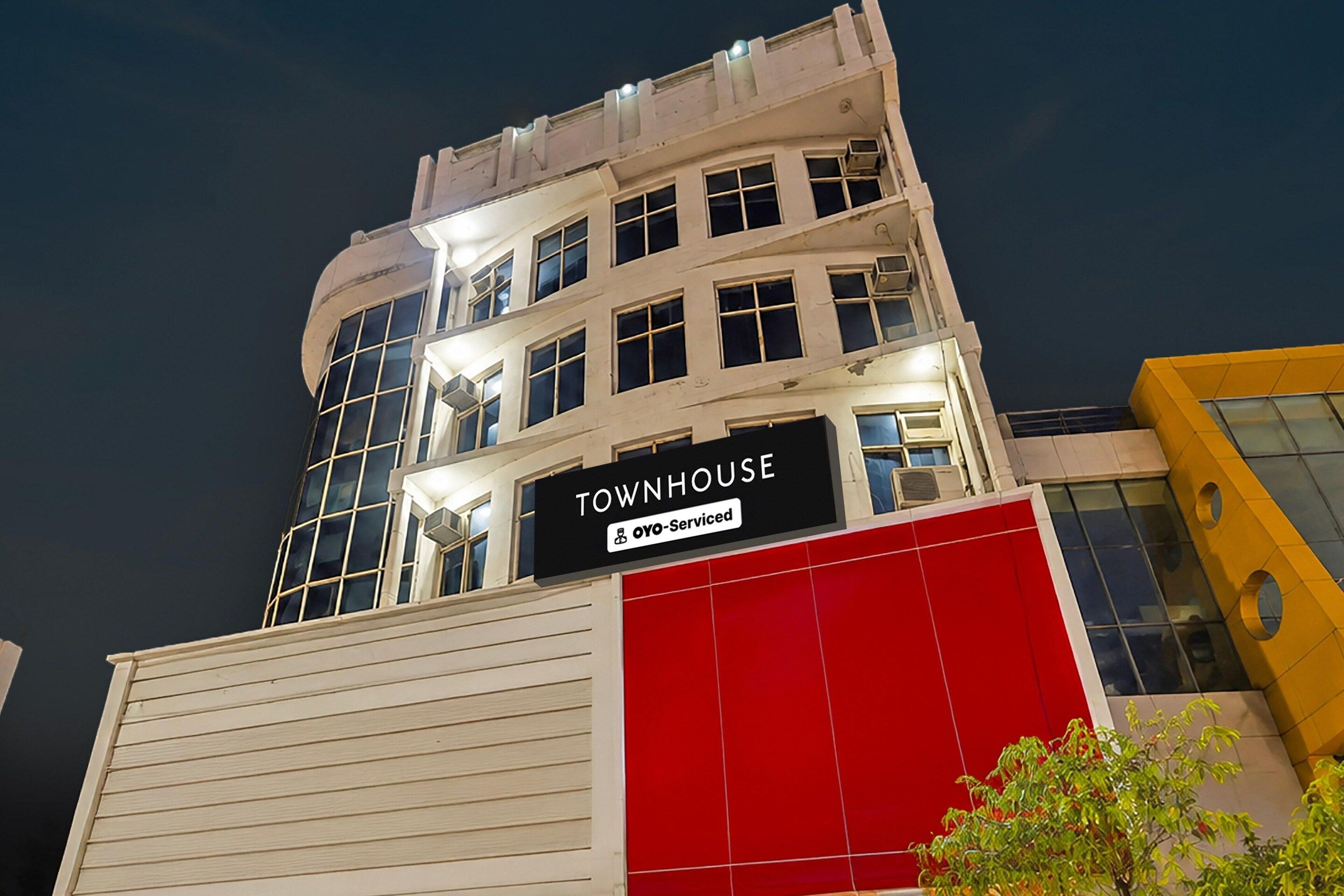 Un edificio a più piani con un cartello che recita 'TOWNHOUSE' e 'OYO-Serviced'.