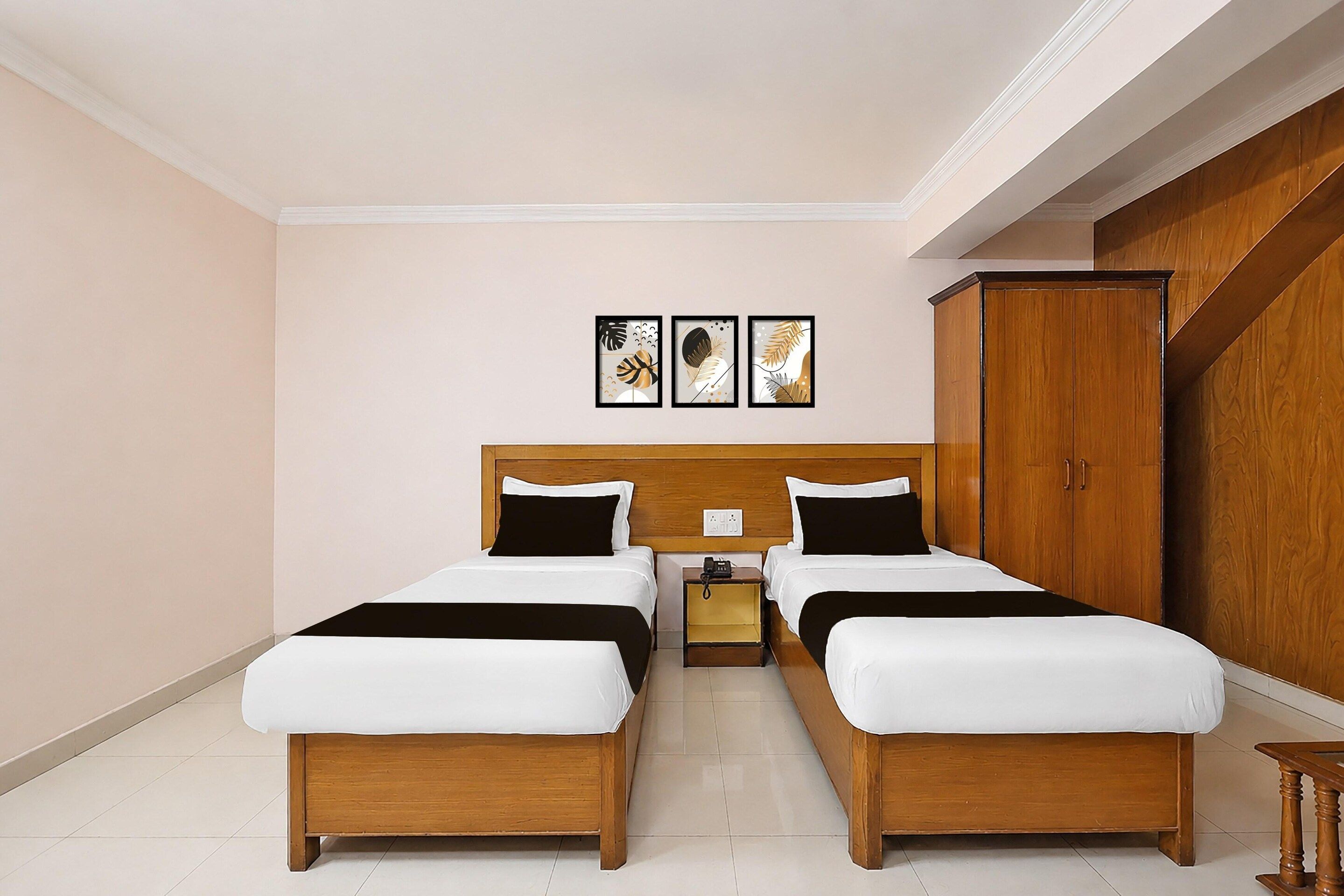 Una habitación de hotel con dos camas, un armario de madera y tres cuadros en la pared.