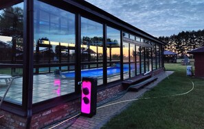 Ein modernes Gebäude mit großen Glasfenstern und Blick auf einen Swimmingpool.