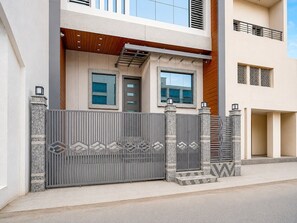 A modern two-story building with a gated entrance, large windows, and a balcony.