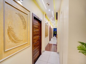A hotel hallway with a wooden door, a potted plant, and a blue wall.