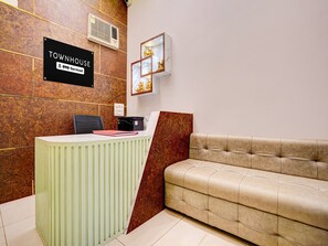A reception area with a reception desk, a sofa, and a sign indicating 'TOWNHOUSE OYO-Serviced.'