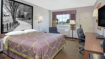 A hotel room with a bed, a desk, a chair, a TV, and a window with curtains.
