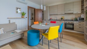 Een moderne keuken met houten kastjes, een eettafel met kleurrijke stoelen en een inbouwoven.