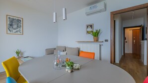 Een moderne woonkamer met een eettafel, banken en een potplant.