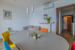 A modern living room with a dining table, sofas, and a potted plant. - Viandante Lake View in Bellano (Bellano)