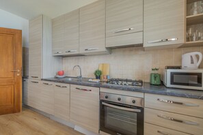 A modern kitchen with wooden cabinets, a stainless steel range, a microwave, and a built-in oven. - Viandante Lake View in Bellano (Bellano)