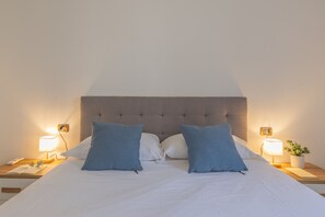 A bed with a tufted headboard, two bedside lamps, and a bedside table with a plant. - Viandante Lake View in Bellano (Bellano)