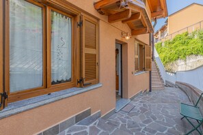 A building with large windows, wooden shutters, and a stone-paved patio. - Viandante Lake View in Bellano (Bellano)