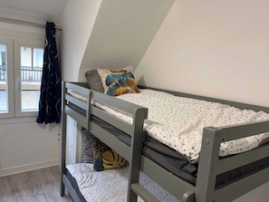 Ein Etagenbett mit Fenster und Vorhängen, ein kleiner Schreibtisch und ein Blick nach draußen.