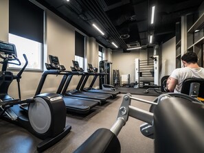 A gym with treadmills, weight machines, and a person exercising.