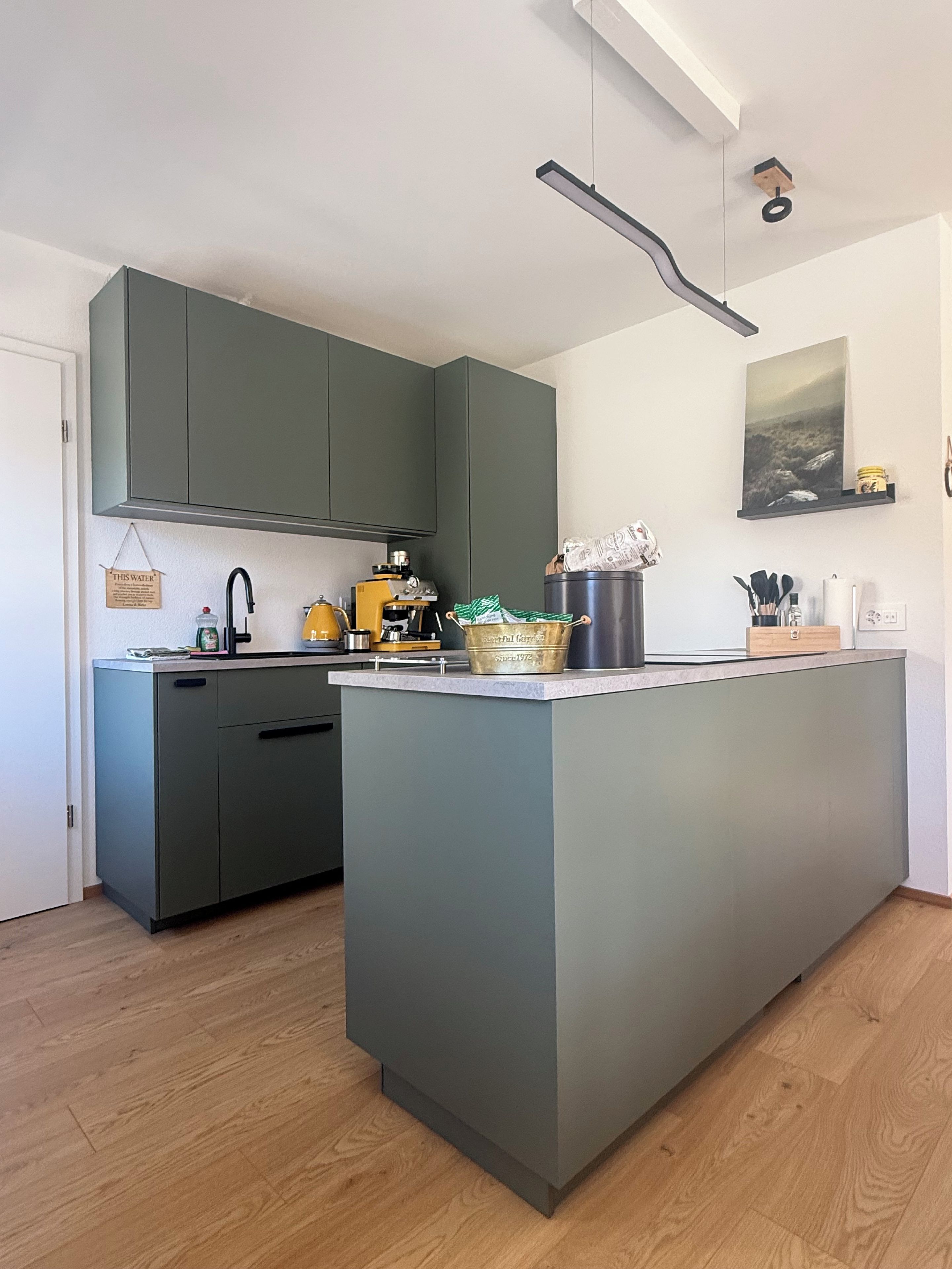 Una cocina moderna con una isla central, armarios grises y una lámpara colgante.