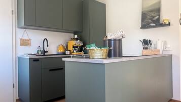 Una cocina moderna con una isla central, armarios grises y una lámpara colgante.