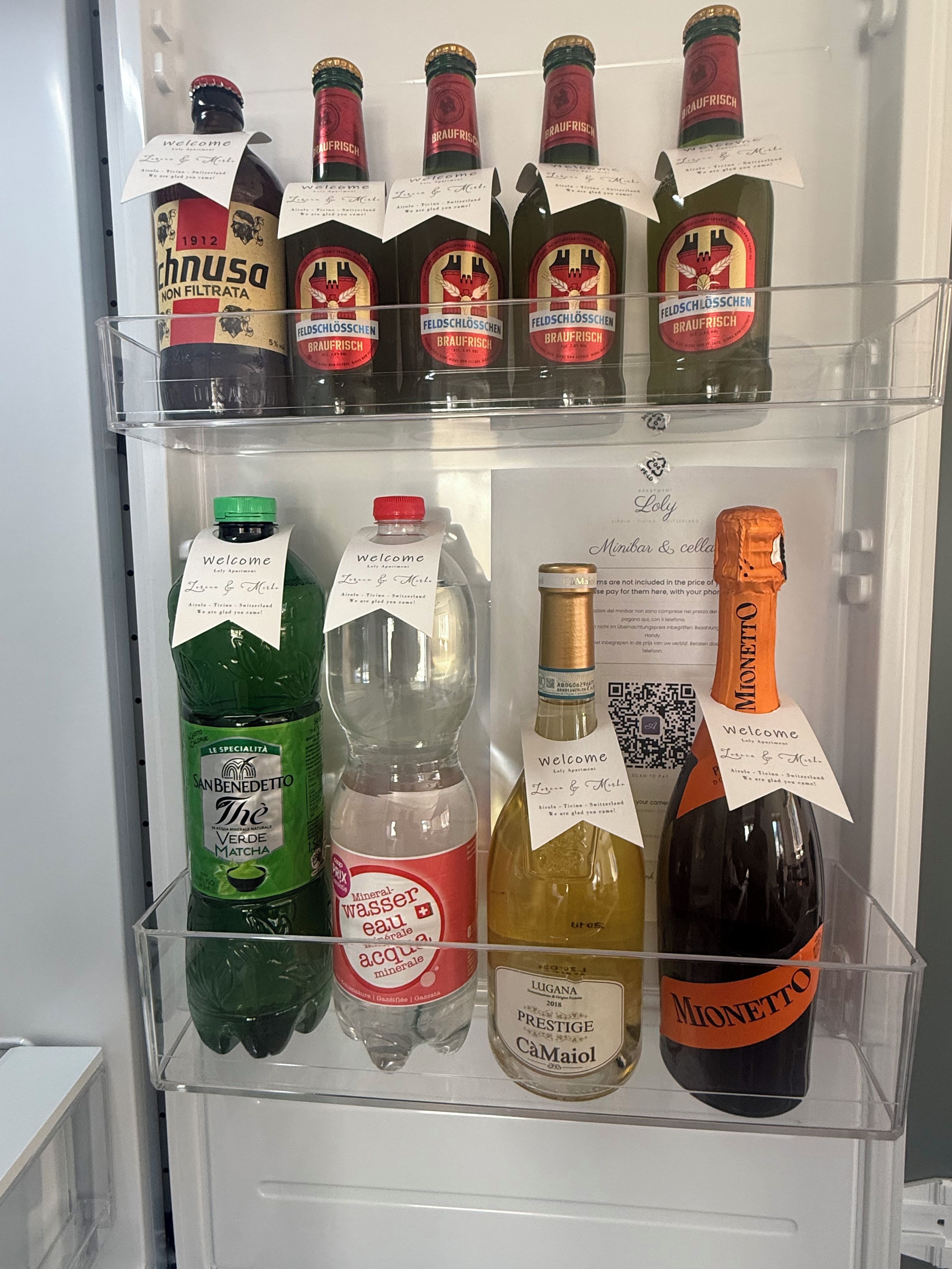 A refrigerator stocked with various beverages including bottled water, mineral water, and alcoholic drinks.