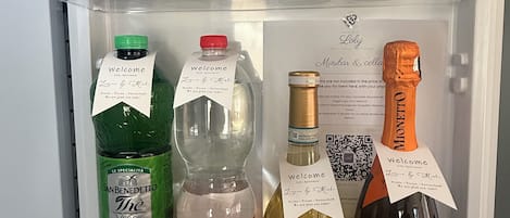 A refrigerator stocked with various beverages including bottled water, mineral water, and alcoholic drinks.