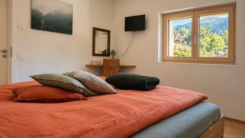 Ein Schlafzimmer mit einem Bett, Kissen, einem Flachbildfernseher, einem Fenster mit Blick und einem Bild an der Wand.