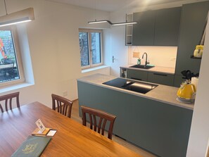 A modern kitchen with a built-in island, a sink, and a yellow kettle.