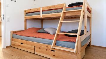 Uma cama beliche com escada, estrutura de madeira e várias almofadas.