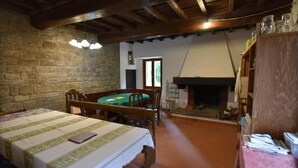 Una habitación rústica con cama, una mesa de comedor, chimenea y paredes de piedra.