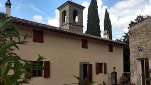 Un edificio con tejado de tejas, una torre con campana y dos árboles altos.