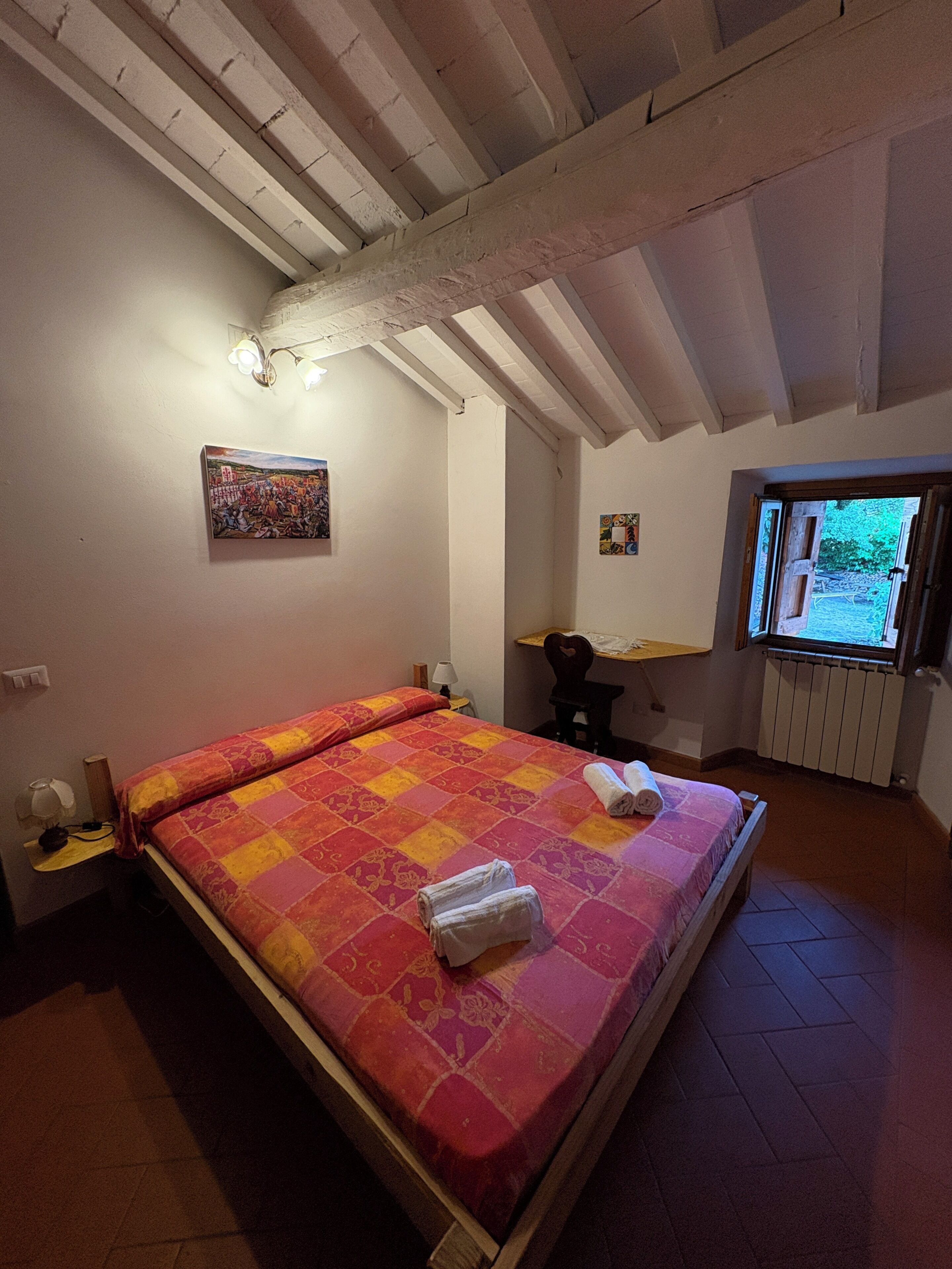 A bedroom with a bed, a desk, a chair, and a window.