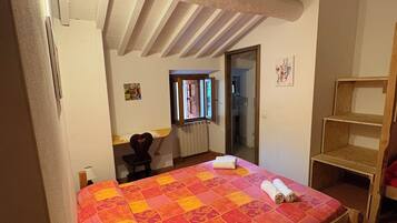 Una habitación con una cama, un escritorio, una silla y un estante de madera.