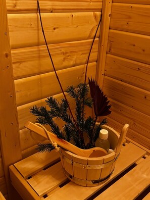 Puisesta laudasta ja kasvia sisältävästä korista varustettu puinen sauna.