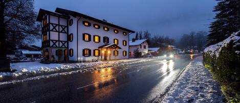 A two-story building with a snow-covered ground, a paved road in front, and a clear sky.