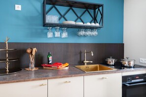 A kitchen with a blue wall, a black shelf with glassware, a sink, and a Bosch oven. - Hochkalter Vacation Rental, 60 square meters (Schönau am Königssee)