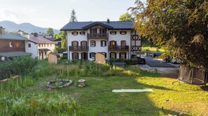 A two-story house with a balcony, surrounded by a grassy yard and parked cars. - Hochkalter Vacation Rental, 60 square meters (Schönau am Königssee)