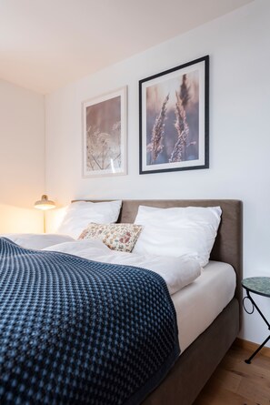 Une chambre d’hôtel avec un lit, une table de chevet et deux tableaux encadrés au mur.