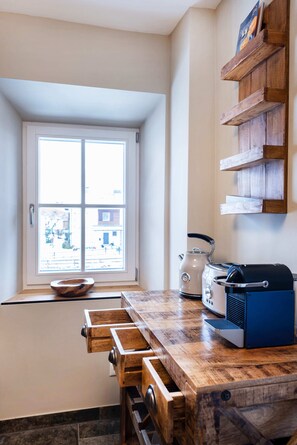 A kitchen with a wooden countertop, a kettle, a toaster, and a window with a view of the outside. - Hochkalter Vacation Rental, 60 square meters (Schönau am Königssee)