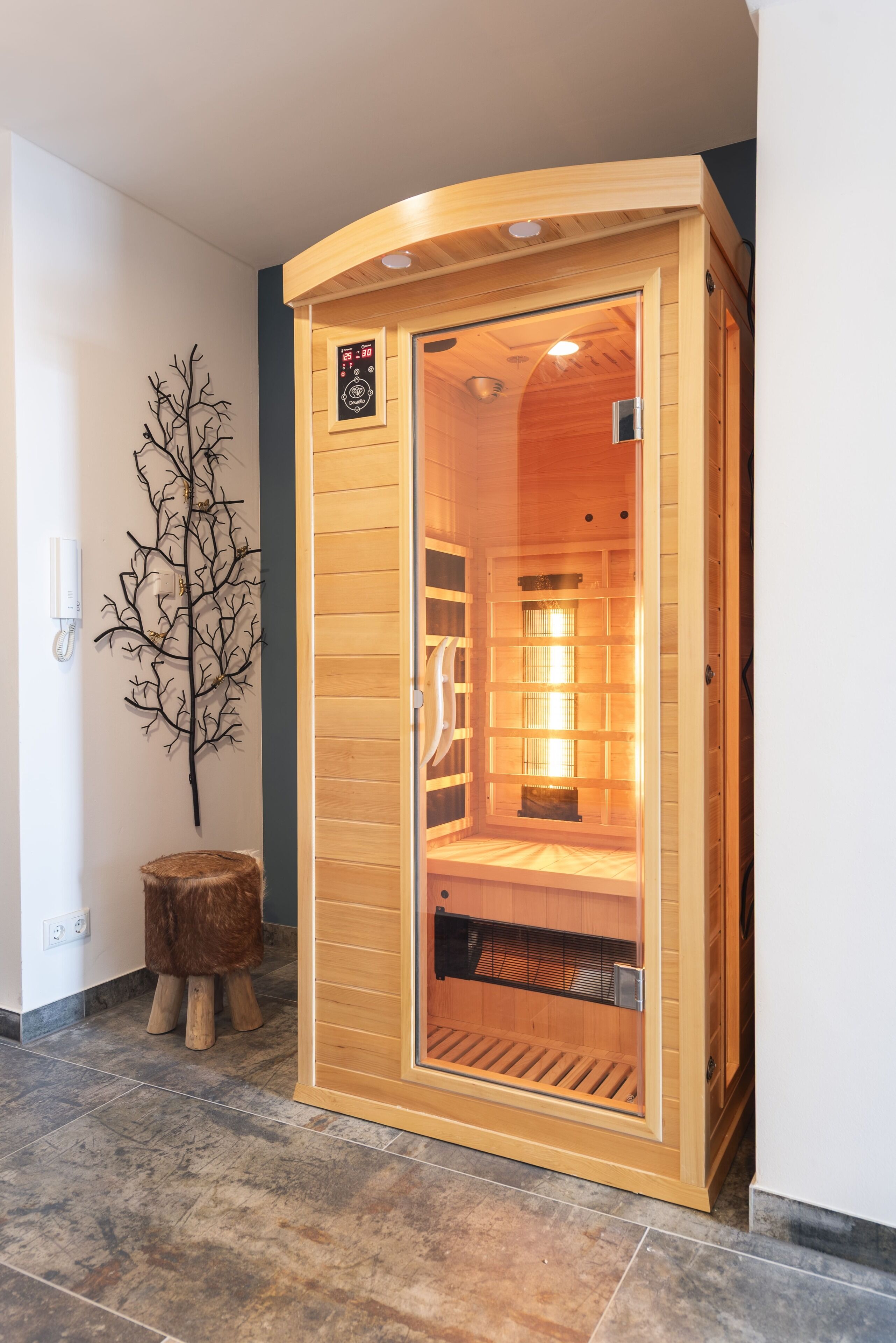 A sauna with a digital control panel, a wooden interior, and a tiled floor.
