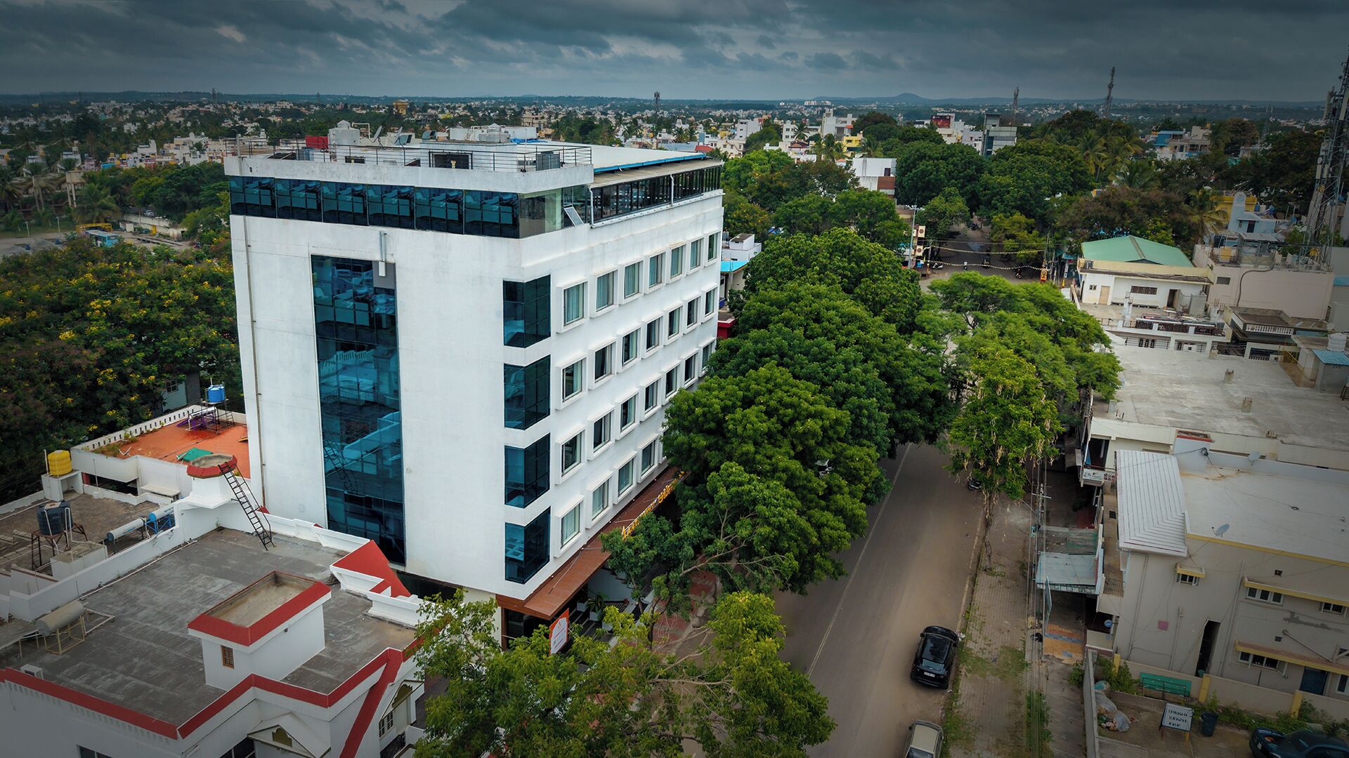 A multi-story building with a modern architectural design, surrounded by greenery and a clear sky.
