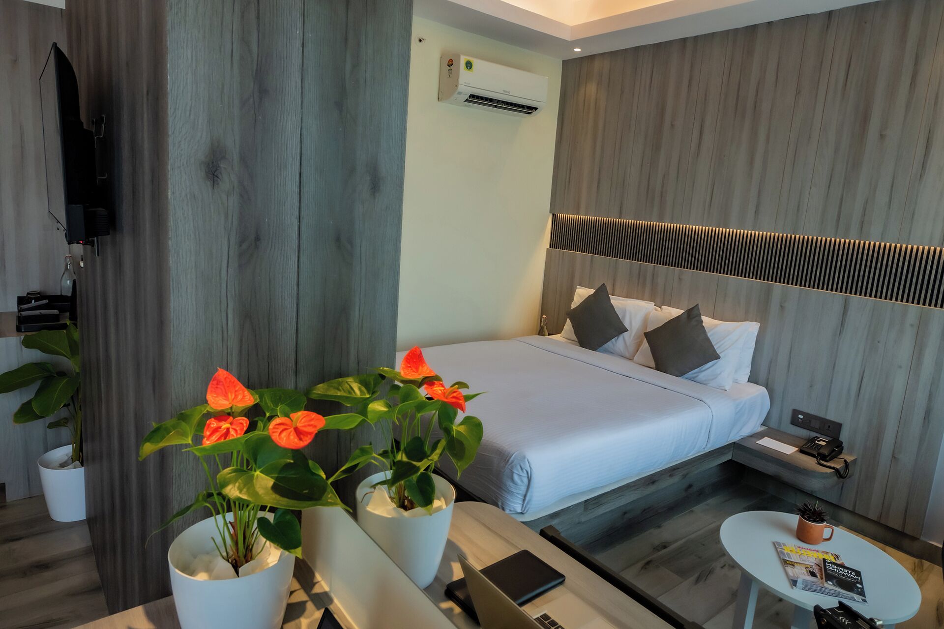 A modern hotel room with a bed, bedside table, and a small round table.