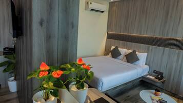A modern hotel room with a bed, bedside table, and a small round table.