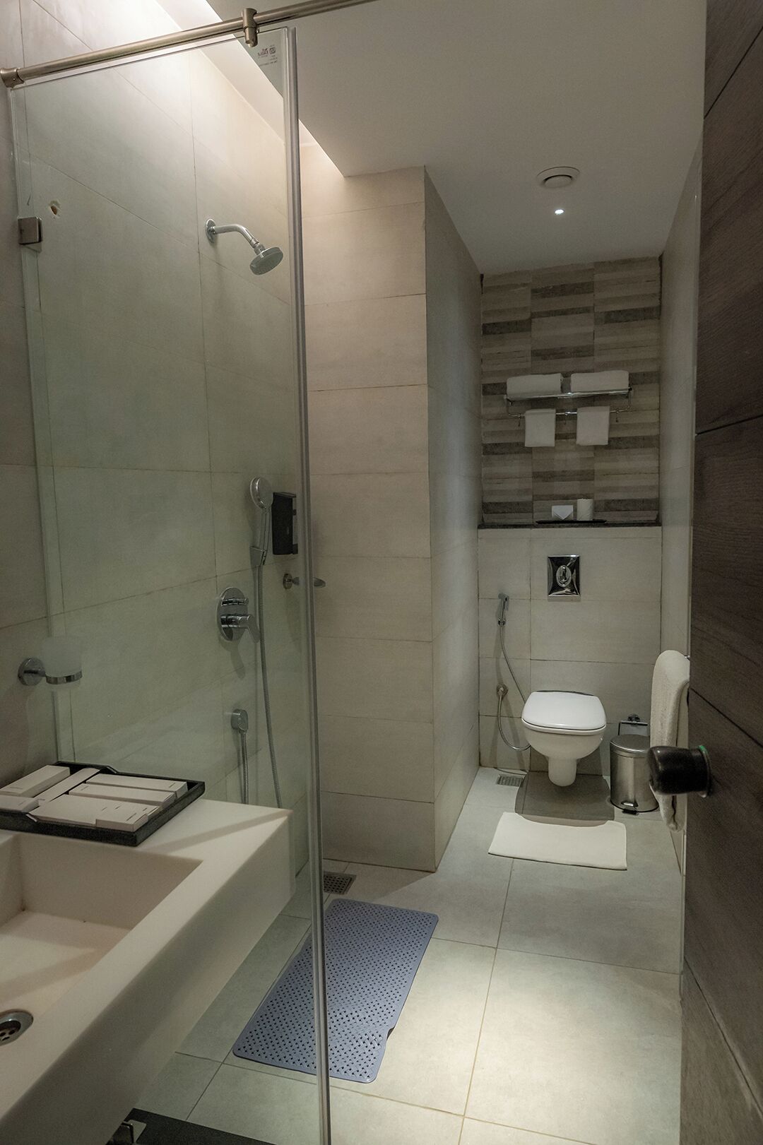 Un baño moderno con ducha de vidrio, bañera blanca, inodoro y lavamanos.