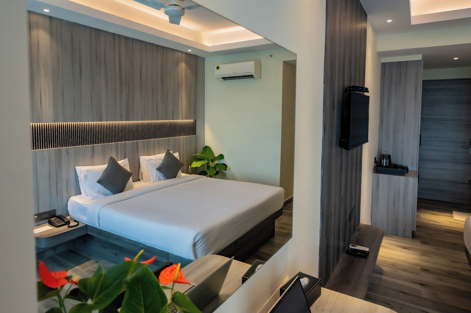 Una habitación de hotel moderna con cama, mesita de noche y televisor de pantalla plana montado en la pared.