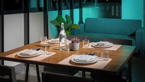 A dining table set for two with plates, cutlery, glasses, and a bottle. - Artis Connect Mysore  (Mysore)