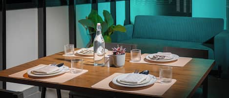 Une table à manger dressée pour deux personnes, avec des assiettes, des couverts, des verres et une bouteille.