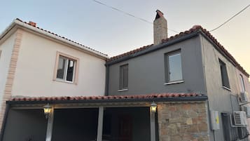 Ein zweistöckiges Gebäude mit einer Steinfassade, einem Ziegeldach und einem Balkon mit Geländer.