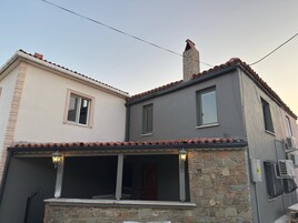 Un edificio de dos pisos con fachada de piedra, techo de tejas y un balcón con barandilla.
