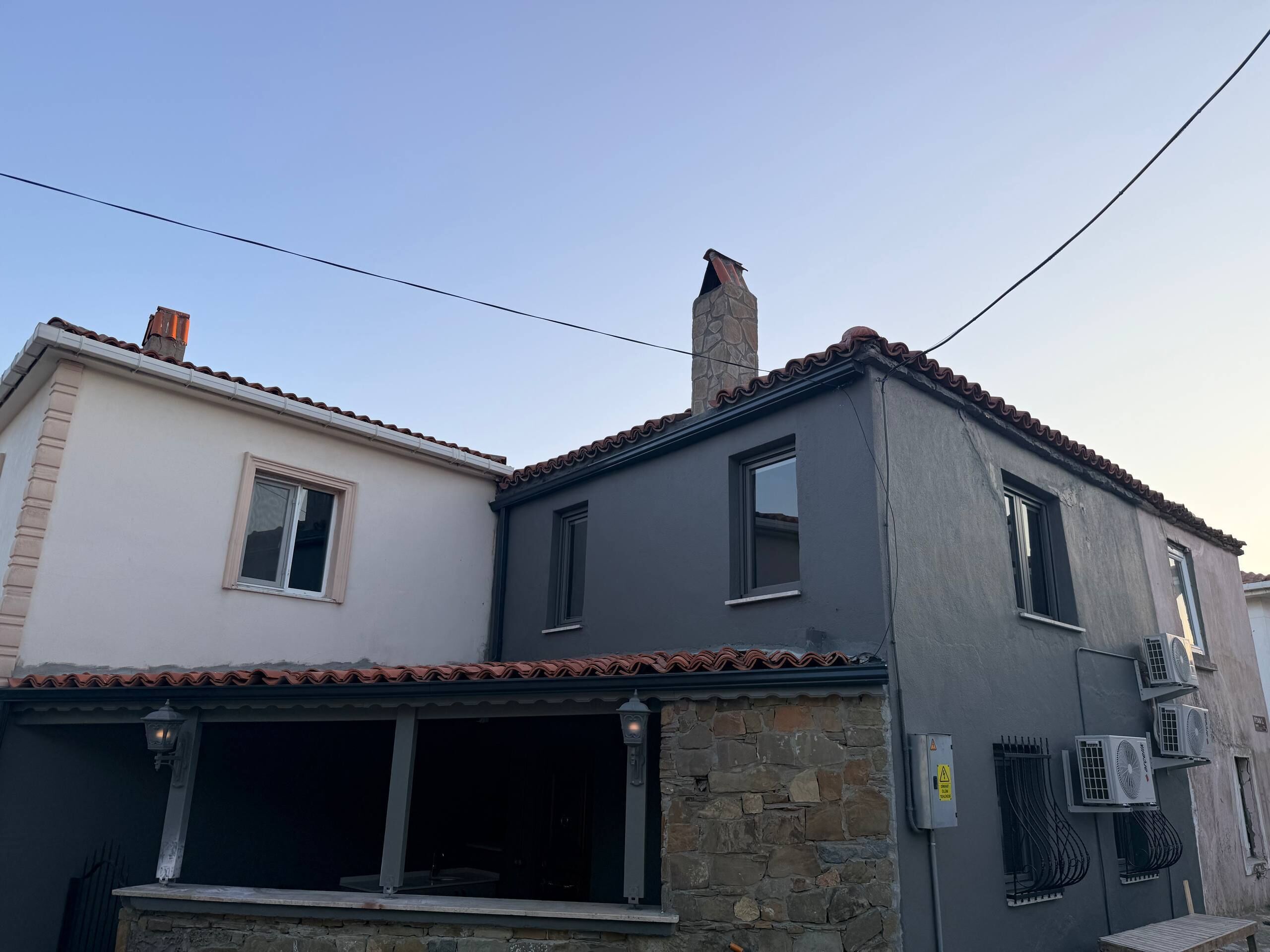 Un edifici de dues plantes amb façana de pedra, teulada de teules i nombroses finestres.