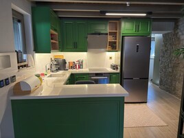 Una cocina moderna con gabinetes verdes, electrodomésticos de acero inoxidable y encimera blanca.