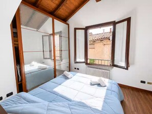 A bedroom with a bed, a window, a radiator, and a wooden ceiling. - Elegant Stay near Lake Como (Maslianico)