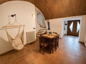 A dining area with a wooden table and chairs, a hanging chair, and a staircase leading to another room. - Elegant Stay near Lake Como (Maslianico)