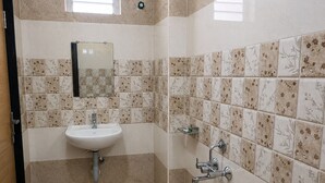 Baño con lavamanos, espejo, ducha y paredes de azulejos.