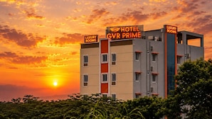 Un edificio de hotel con letreros que indican 'Luxury Rooms' y 'GVR Prime' bajo un cielo al atardecer.